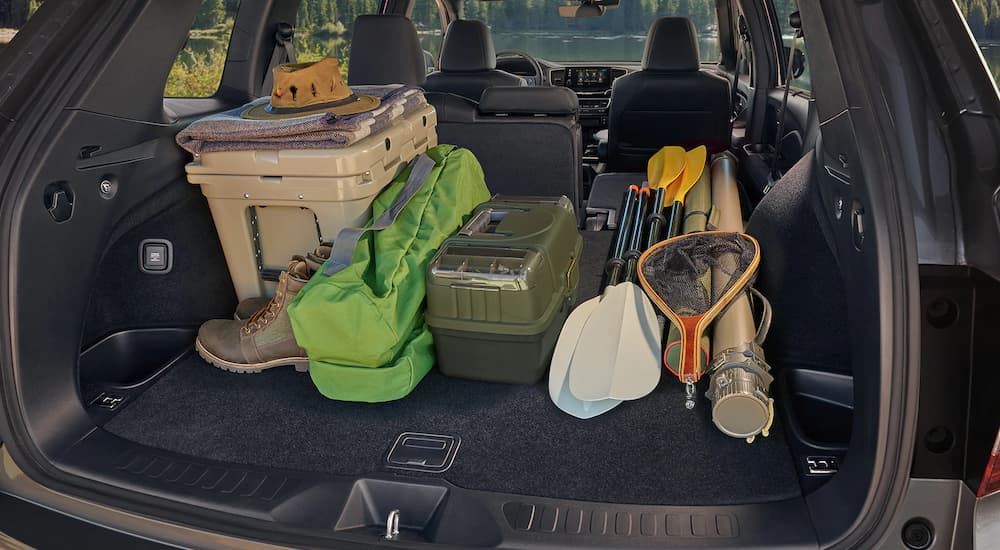 The rear cargo area of a 2022 Honda Passport is shown loaded with camping gear.