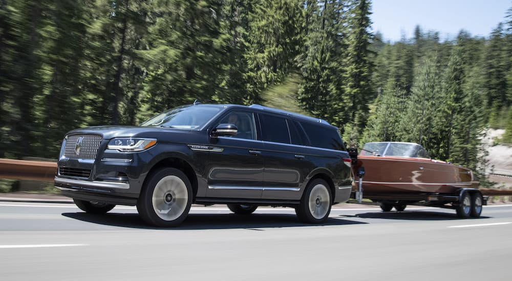 A grey 2022 Lincoln Navigator is shown towing a boat.