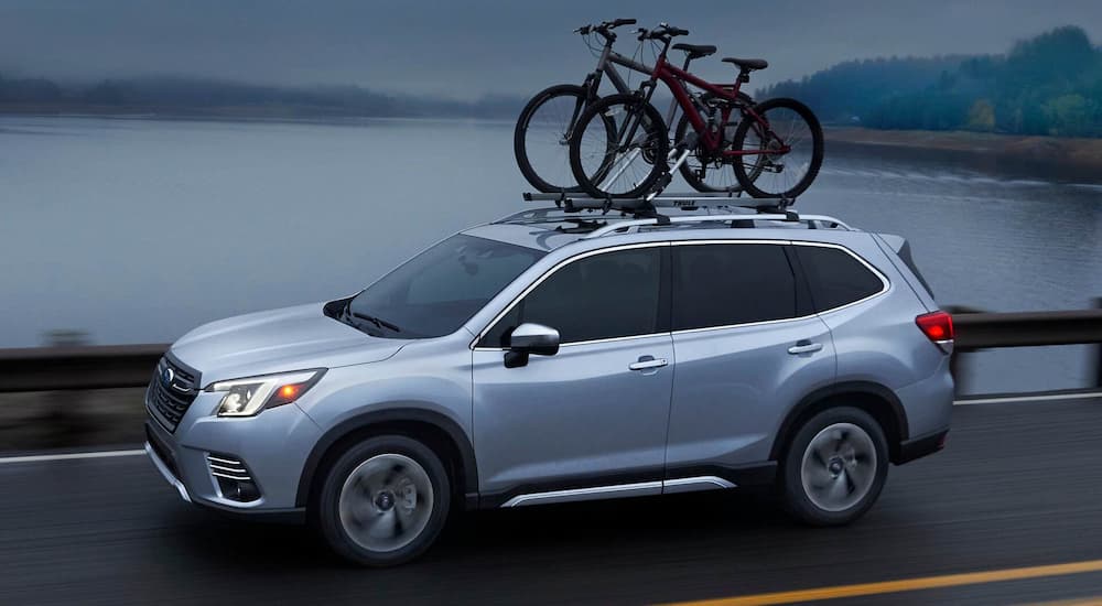 A silver 2022 Subaru Forester Touring is shown driving past a body of water during a 2022 Nissan Rogue vs 2022 Subaru Forester comparison.