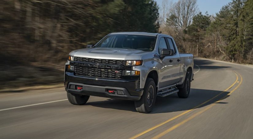 A silver 2020 Chevy Silverado 1500 Z71 Trail Boss is shown rounding a corner after visting a certified pre-owned Chevy Silverado dealer.