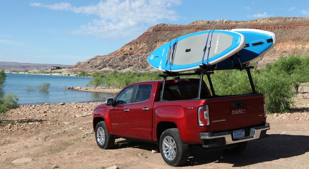 A red 2019 GMC Canyon SLT is shown from a rear angle near a body of water.