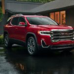 A red 2020 certified pre-owned GMC Acadia is shown parked outside of a modern home.