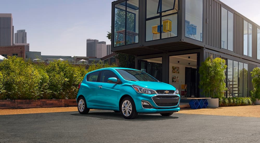 A blue 2022 Chevy Spark is shown parked outside of a modern home.
