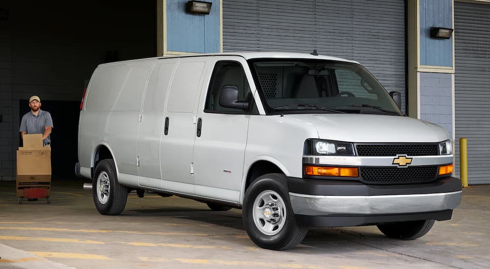 A white 2022 Chevy Express Van is shown parked outside of a warehouse.
