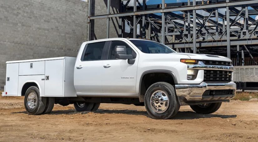 A white 2022 Chevy Silverado 3500HD Chassis Cab is shown parked at a construction site after leaving a commercial truck dealer.