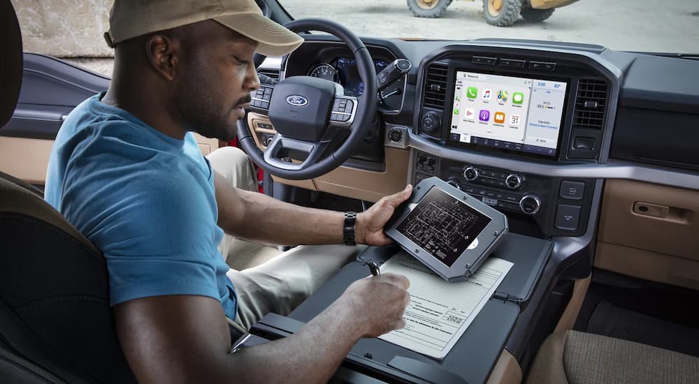 A man is shown working in the cab of a 2021 Ford F-150.