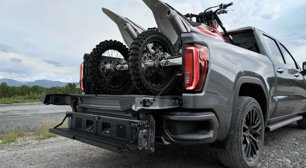 A grey 2022 GMC Sierra 1500 shows the MultiPro Tailgate and two dirt bikes in the bed.
