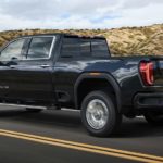 A blue 2022 GMC Sierra 2500HD Denali is shown cruising down an empty highway.