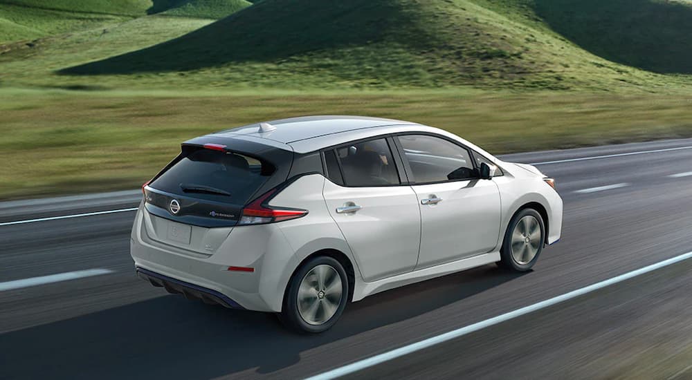 A white 2020 Nissan LEAF is shown driving past rolling hills.