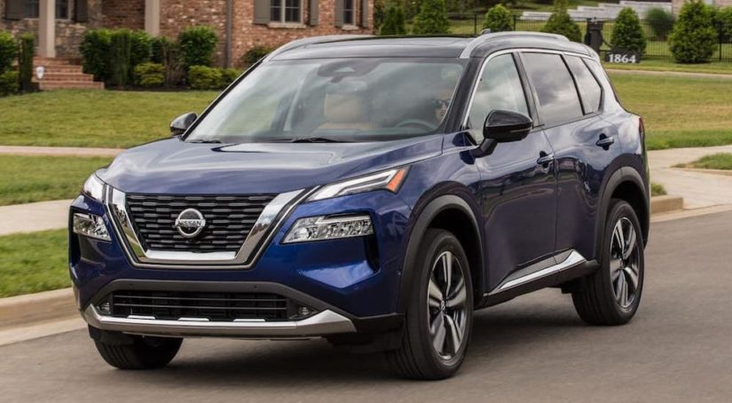 A dark blue 2020 Nissan Rogue is shown driving on a suburban street after leaving a Nashville used Nissan dealership.