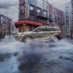 A green 2017 Subaru Forester is shown splashing through a puddle on a city street.
