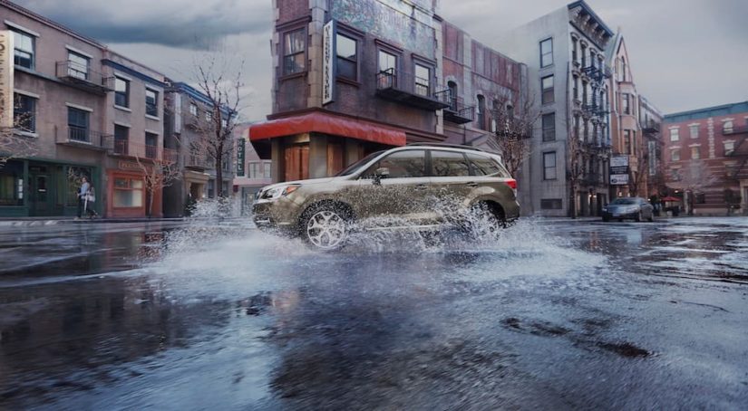 A green 2017 Subaru Forester is shown splashing through a puddle on a city street.