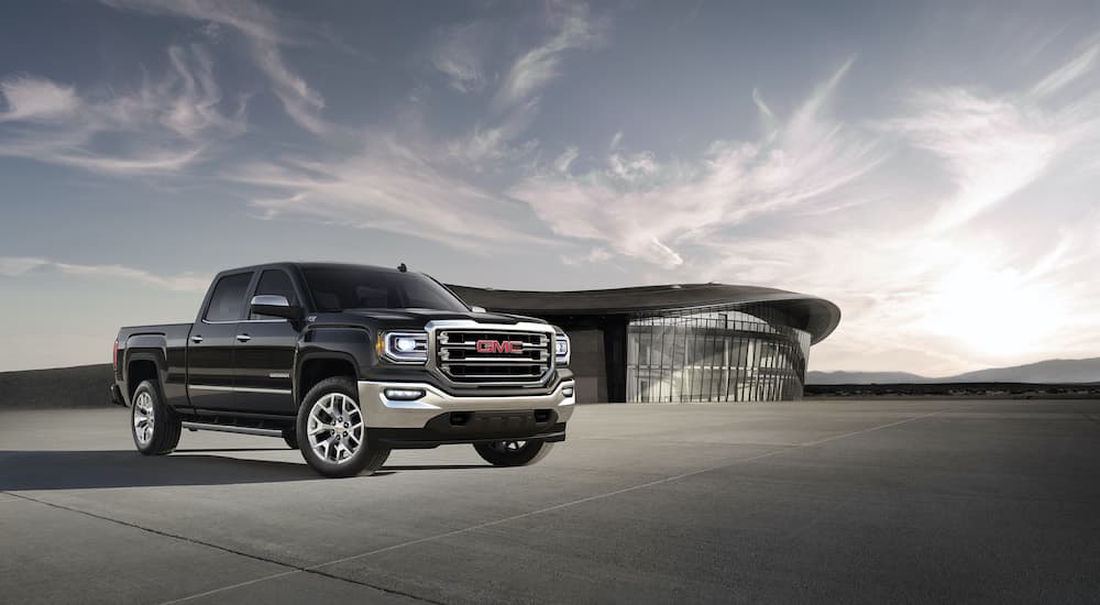 A black 2018 GMC Sierra 1500 SLT is shown parked in front of a modern building.