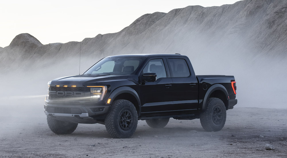 A black 2021 Ford F-150 Raptor is shown parked in a desert area.