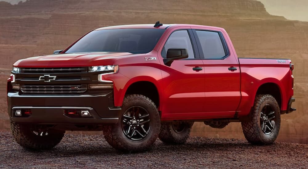 A red 2021 Chevy Silverado 1500 LT Trailboss is shown parked in an open dirt lot.