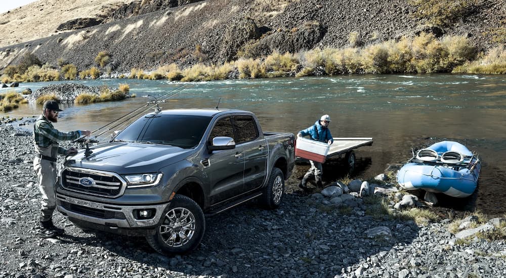 A grey 2022 Ford Ranger Lariat is shown with a small boat near a river bank.