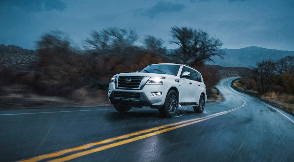 A white 2022 Nissan Armada is shown driving during a 2022 Chevy Tahoe vs 2022 Nissan Armada competition.