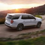 A white 2022 Chevy Tahoe is shown on a dirt road during a 2022 Chevy Tahoe vs 2022 Toyota Sequoia competition.