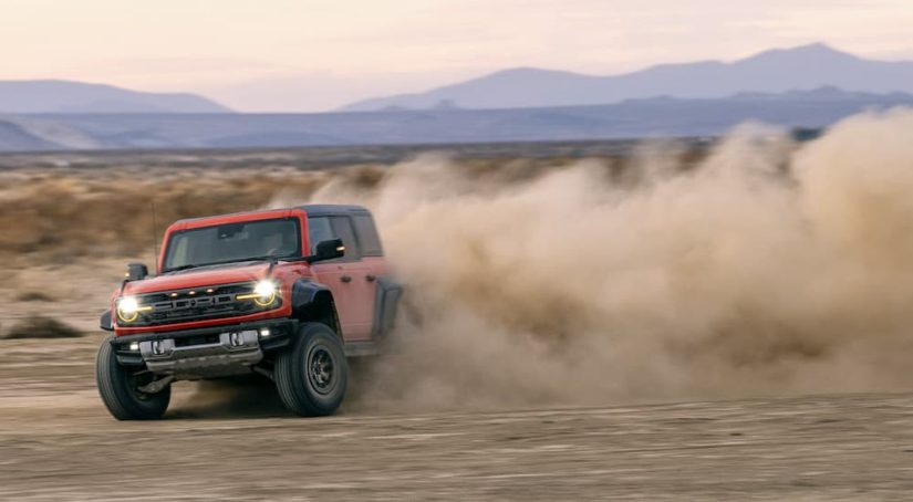 An orange 2022 Ford Bronco Raptor is shown sliding through dirt at speed after leaving a fremont county ford dealership.