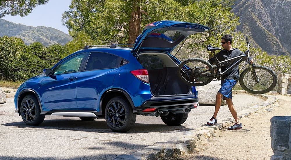 A blue 2022 Honda HR-V Sport is shown with a bike being loaded into the trunk.