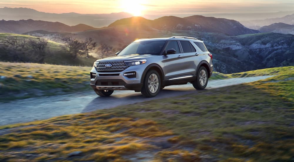A silver 2022 Ford Explorer is shown driving on an open road in the mountains.