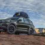 A green 2022 Ford Explorer Timberline is shown driving on a mountain trail during a 2022 Ford Explorer vs 2022 Honda Pilot competition.