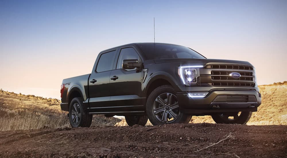A black 2022 Ford F-150 Lariat is shown parked in a dirt lot.