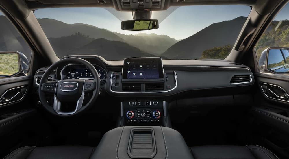 The black interior of a 2022 GMC Yukon shows the steering wheel and center console.