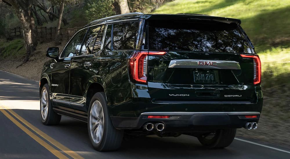 A black 2022 GMC Yukon XL Denali is shown from the rear driving on a road.