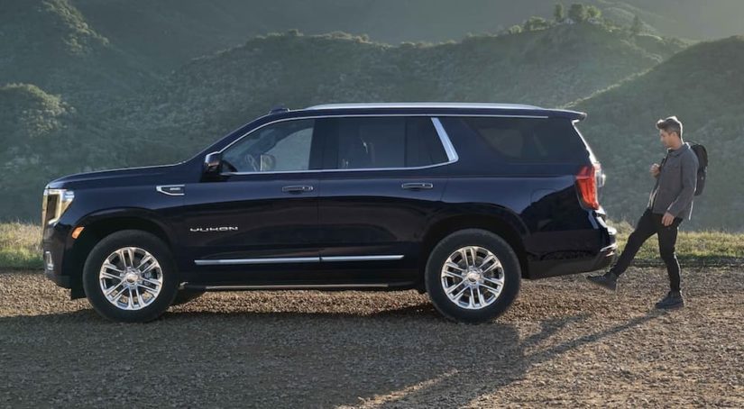 A black 2022 GMC Yukon XL is shown from the side parked on a of a mountain trail.