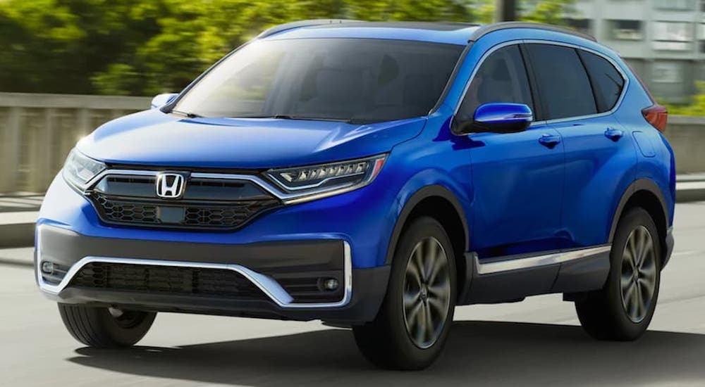 A blue 2022 Honda Crv is shown from the front at an angle while it drives down the road.