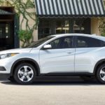 A white 2022 Honda HR-V LX is shown from the side parked outside of a storefront.