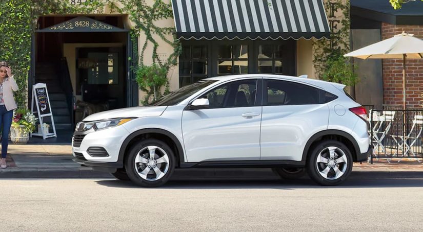 A white 2022 Honda HR-V LX is shown from the side parked outside of a storefront.