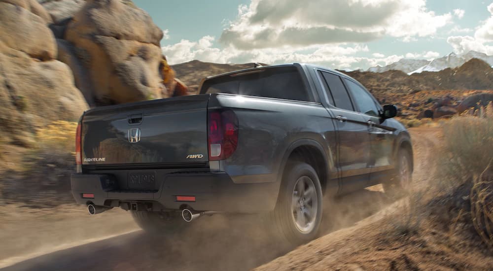 A grey 2022 Honda Ridgeline RTL-E is shown from the rear driving on a desert road.