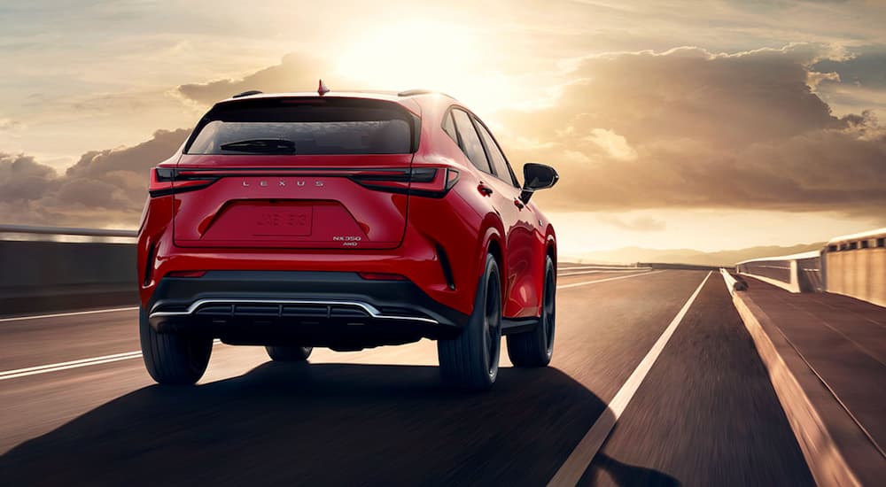 A red 2022 Lexus NX is shown from the rear driving on an open highway.