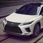 A white 2022 Lexus RX is shown driving on a city street.