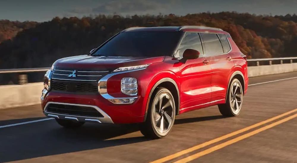 A red 2022 Mitsubishi Outlander is shown from the front at an angle while driving down the road.