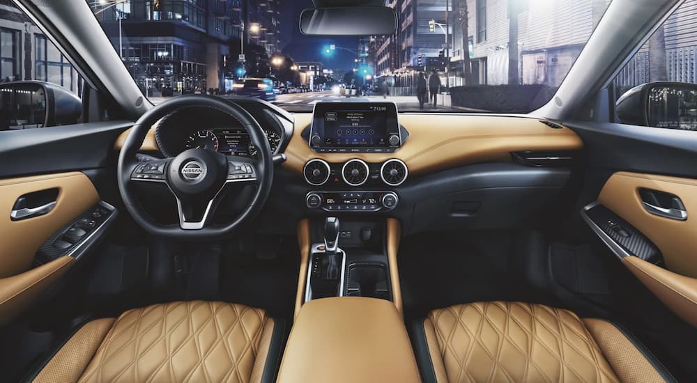 The black and tan interior of a 2022 Nissan Sentra shows the steering wheel and center console.