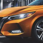 A close up of the front grille and headlight on an orange 2022 Nissan Sentra is shown.