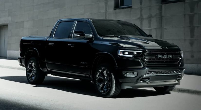 A black 2022 Ram 1500 is shown from the front at an angle parked in front of a concrete building after searching "CDJR dealer near me."