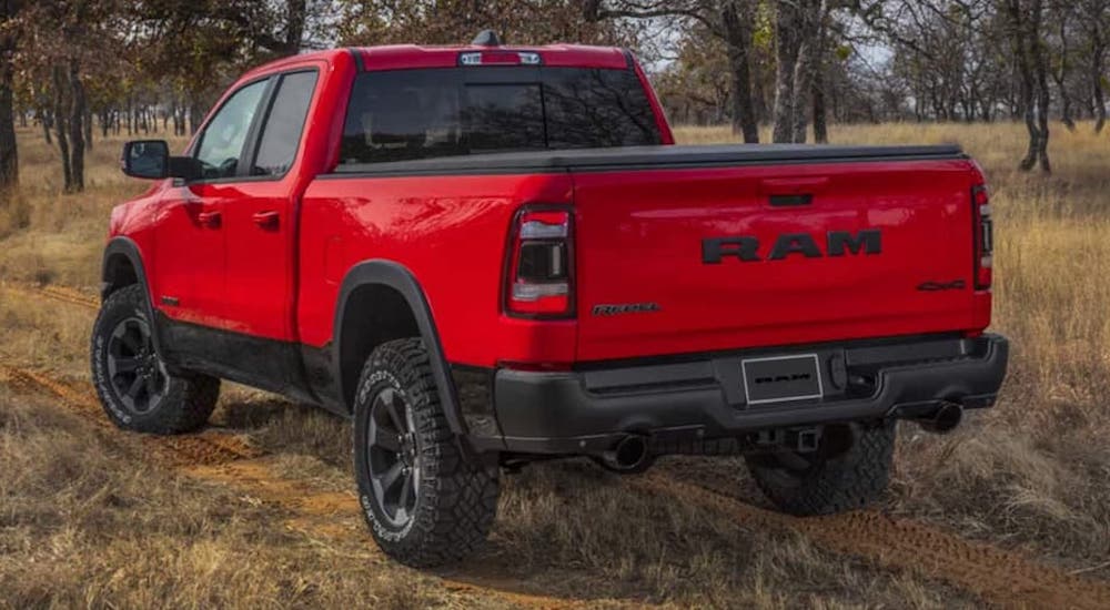 A red 2022 Ram 1500 Rebel is shown from the rear at an angle in the woods.