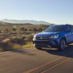 A blue 2022 Volkswagen Taos is shown driving on an open road.