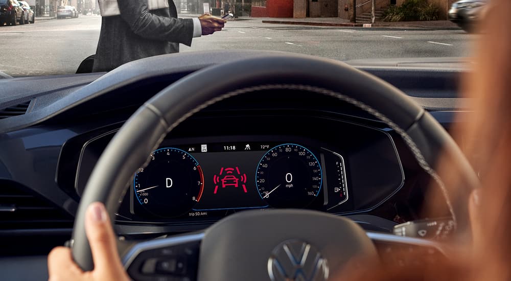 A woman is shown driving a 2022 Volkswagen Taos through a city.