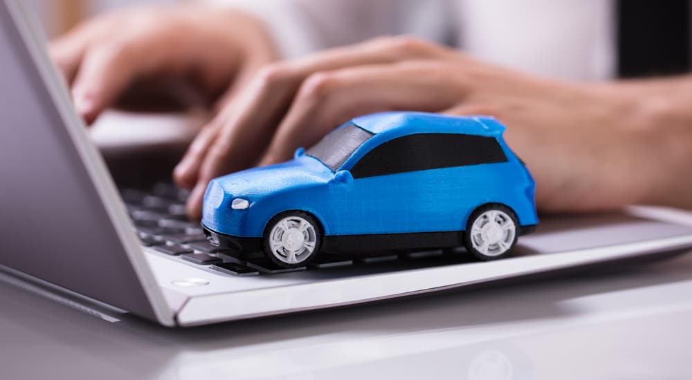 A blue toy car is shown on a laptop.