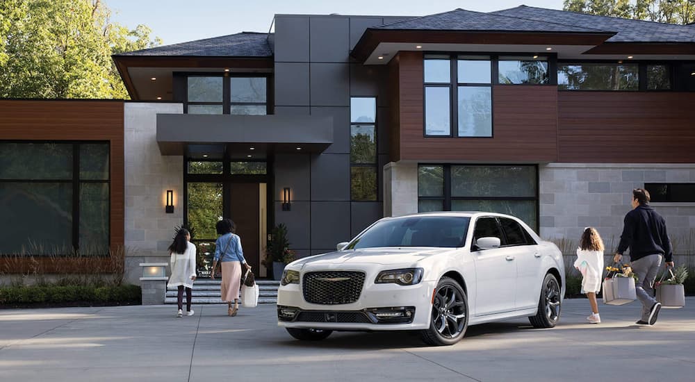 A white 2021 Chrysler 300S is shown parked outside of a modern home.