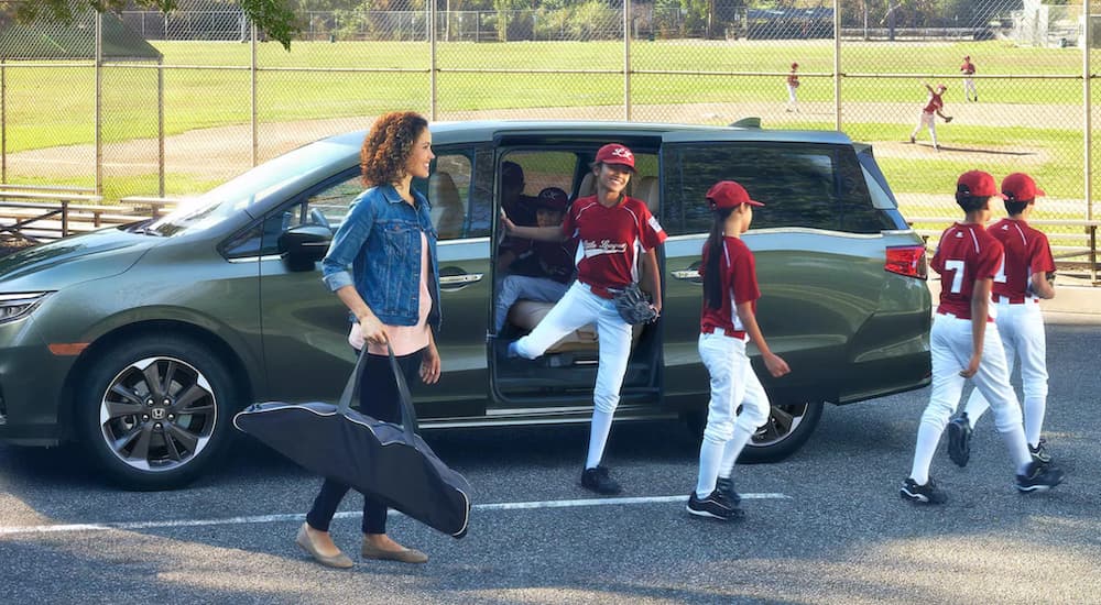 A mom is shown getting a group of kids ready for baseball practice near a green 2021 Honda Odyssey.