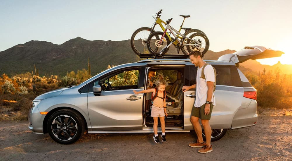 A family is shown getting out of a silver 2021 Honda Odyssey Elite.