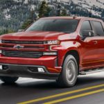 A red 2021 Chevy Silverado 1500 is shown on an open road after visiting a certified pre-owned Silverado dealer.