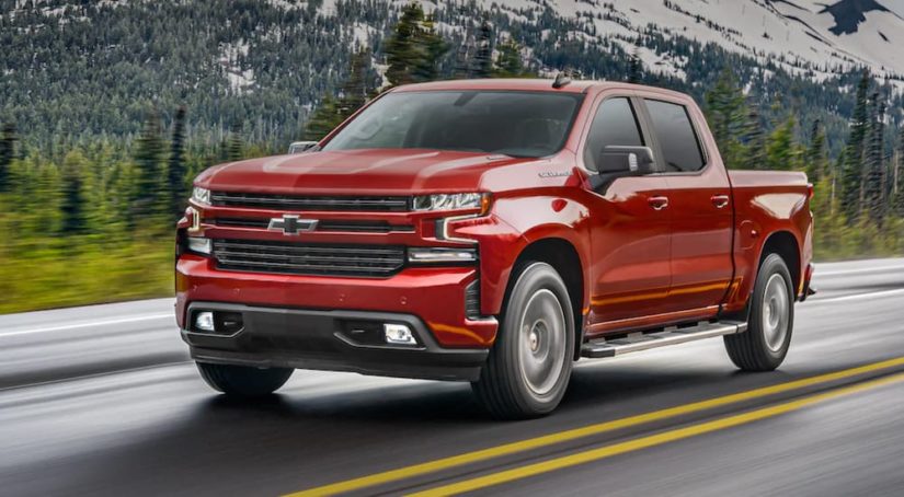 A red 2021 Chevy Silverado 1500 is shown on an open road after visiting a certified pre-owned Silverado dealer.