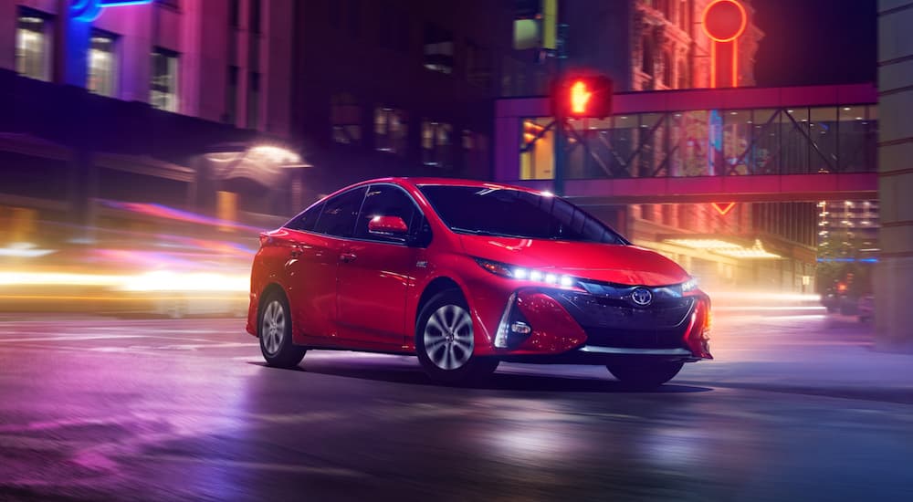 A red 2020 Toyota Prius is shown driving through a city at night.